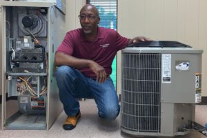 A man kneeling down next to an air conditioner.