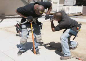 Two men working on a sidewalk with tools.