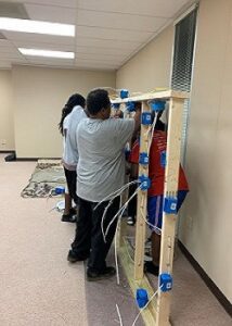 A group of people working on some wall mounted shelves.