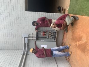 Three men working on a residential electrical panel.